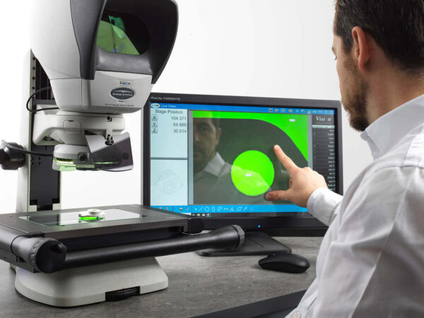 Opérateur utilisant le système de mesure optique et vidéo Swift PRO Duo pour contrôler une pièce de précision sur platine, avec affichage des mesures à l’écran.
